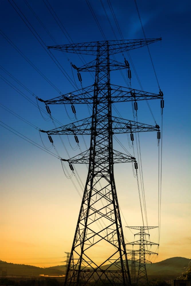 Electrical transmission towers and power lines silhouetted against a sunset sky
