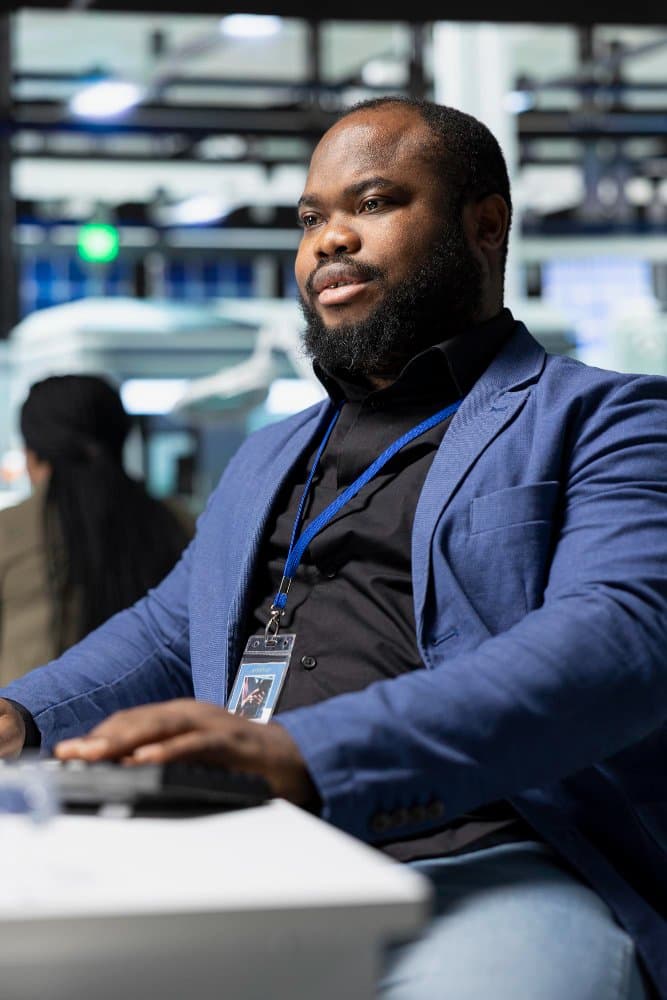 A government IT professional with an access badge working at a control room workstation